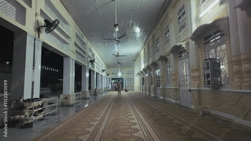 View of ceiling fans then showing a long corridor with people in distance inside Ilyasi Masjid View of ceiling fans then showing a long corridor with people in distance inside Ilyasi Masjid