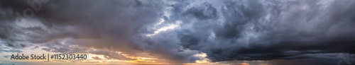 Panorama of a stormy sky with sunlight and dark rain clouds as a texture or background