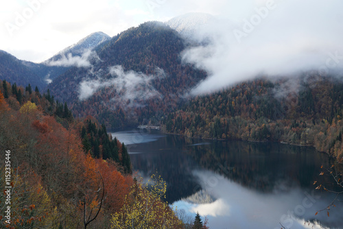 Autumn mountains in clouds reflected in waters of lake Ritsa. Abkhazia. Georgia photo