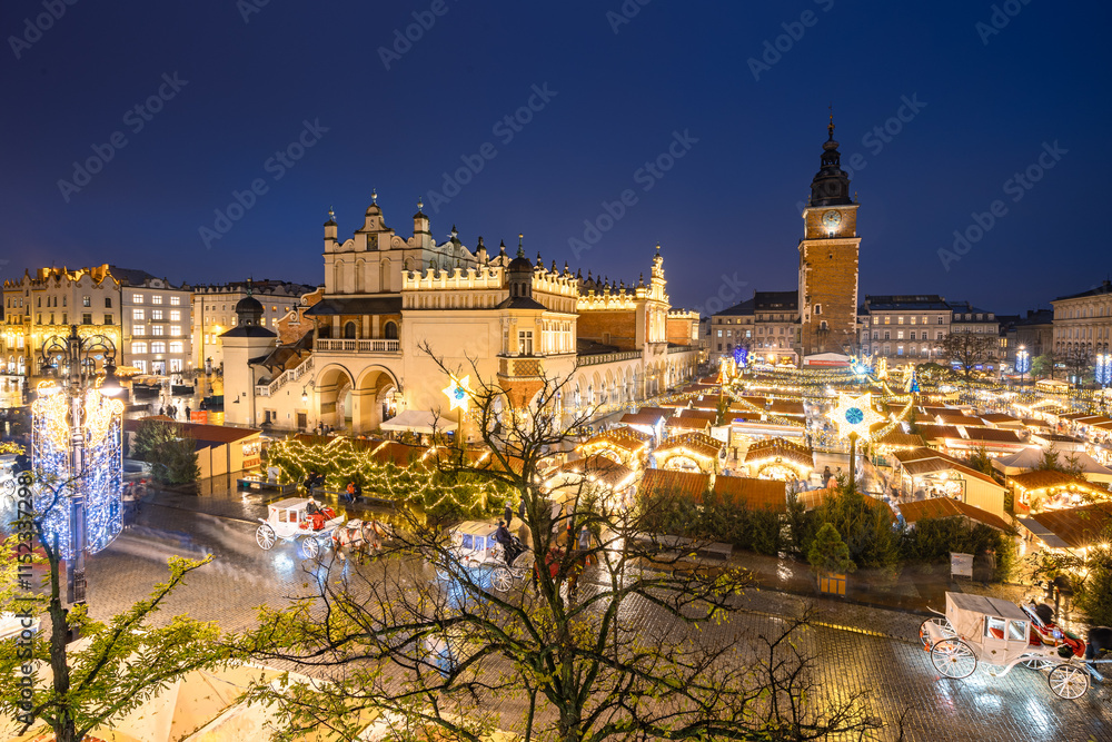 Fototapeta premium View of the Krakow Christmas Market 2024 and the historic Old Town Square, beautifully illuminated with festive lights and vibrant holiday atmosphere.