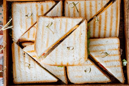 A beautifully curated selection of mouthwatering sandwiches is neatly arranged in a rustic wooden box, creating an appealing visual display that truly captivates the eye and draws in admirers photo