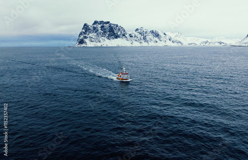 A small boat is gently navigating through the icy waters that are located near the snowy cliffs