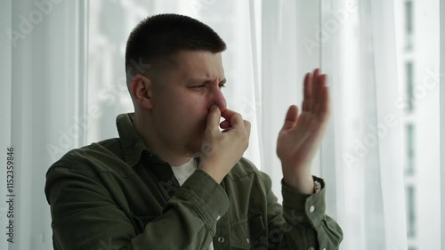 The man gestures that it stinks very strongly.
The stench is strong and the man feels sick.
A man covers his nose from the strong stench.
Someone spoiled the air