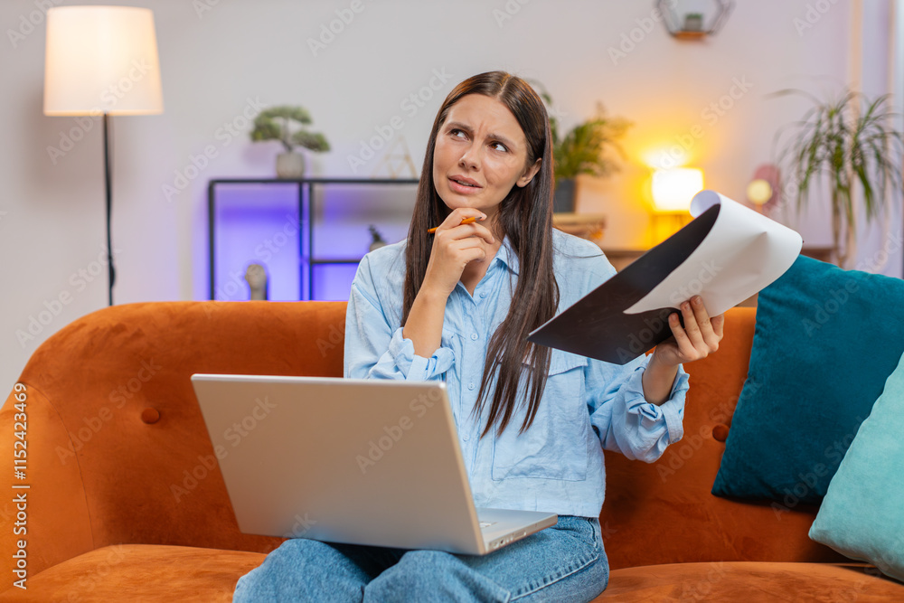 Young woman freelancer accountant working with financial documents, calculate taxes for charts and graph reports of home income on couch. Girl working on laptop computer, planning expenses budget Young woman freelancer accountant working with financial documents, calculate taxes for charts and graph reports of home income on couch. Girl working on laptop computer, planning expenses budget