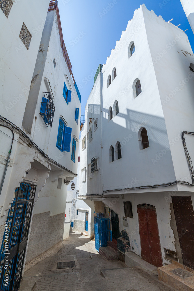 Fototapeta premium narrow, winding alleyway in a traditional Moroccan medina, with whitewashed buildings, colorful doors, and intricate architectural details, creating a picturesque and authentic scene