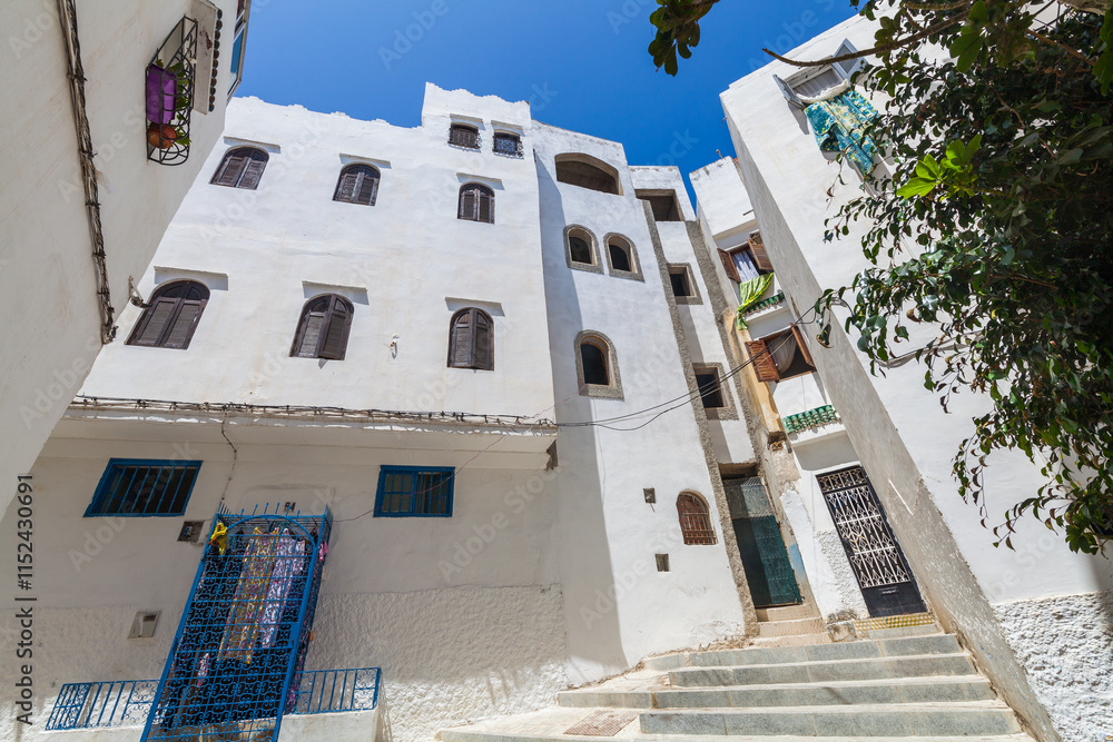 Fototapeta premium narrow street ascending between whitewashed buildings with colorful accents, creating a picturesque and characteristic scene in a Mediterranean town