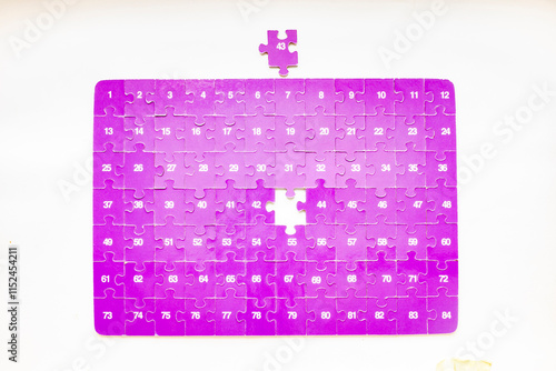 Purple jigsaw puzzle peaces with numbers in white color, the number 43 missing piece not placed yet. Overhead directly above view with light reflection, isolated on a white background photo