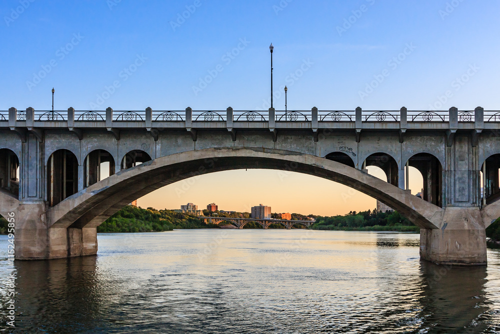 A bridge spans a river with a city in the background A bridge spans a river with a city in the background