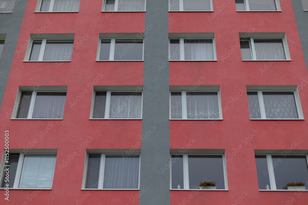 The red apartment building facade features an array of multiple windows combined with a gray structure