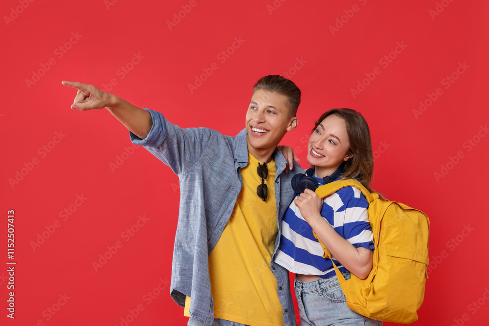 Obraz premium Traveller with backpack. Happy woman and man pointing at something on red background