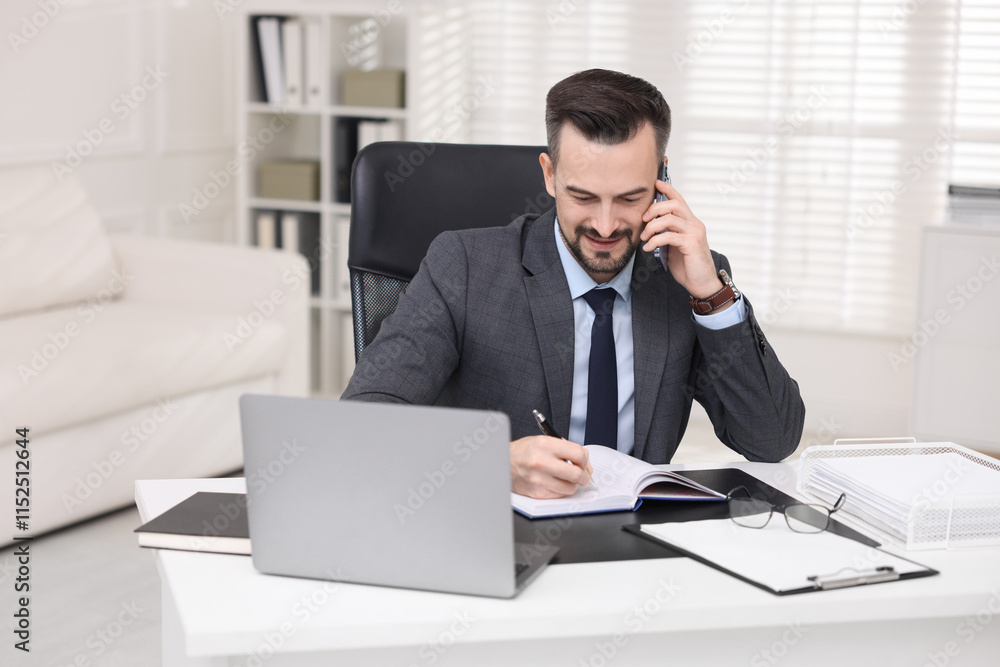 Happy banker talking on smartphone at table in office Happy banker talking on smartphone at table in office