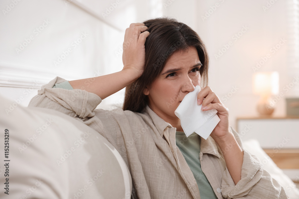Young woman with tissue blowing runny nose at home Young woman with tissue blowing runny nose at home