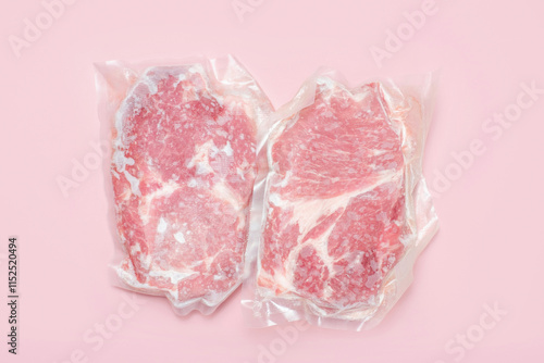 Two pieces of pork meat packed in a vacuum bag close-up on a pink background top view.
