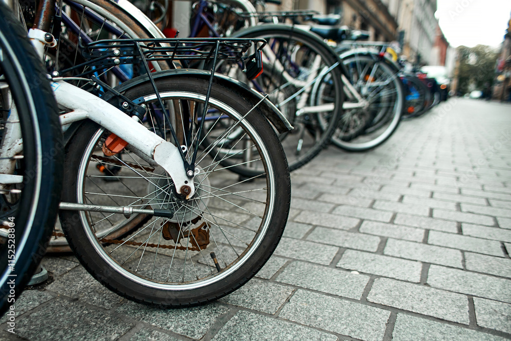 Close-up of a wheel in a row of parked bicycles on the streets of Europe. Close-up of a wheel in a row of parked bicycles on the streets of Europe.