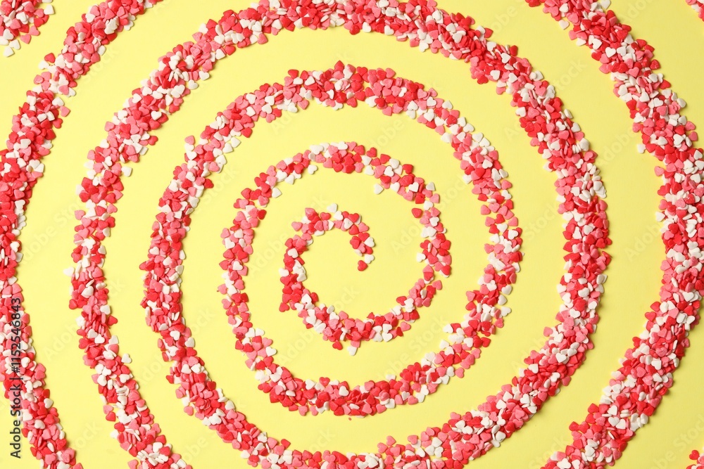 Spiral made of bright heart shaped sprinkles on yellow background, flat lay Spiral made of bright heart shaped sprinkles on yellow background, flat lay