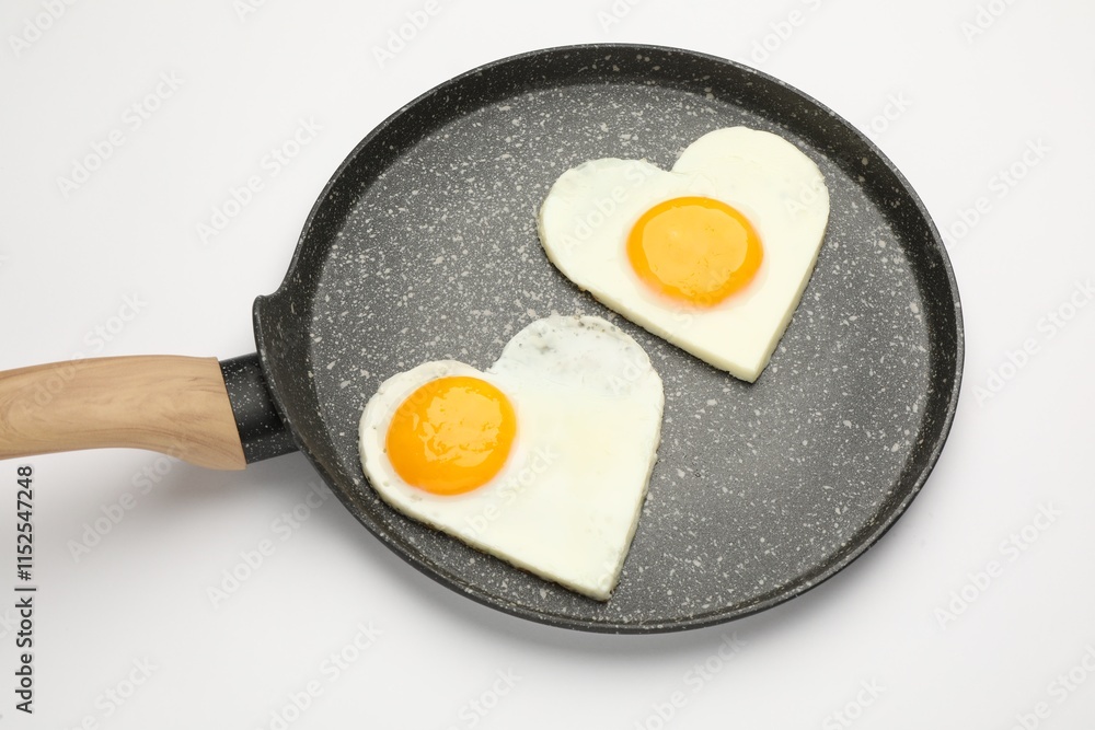 Heart shaped fried eggs in frying pan isolated on white Heart shaped fried eggs in frying pan isolated on white