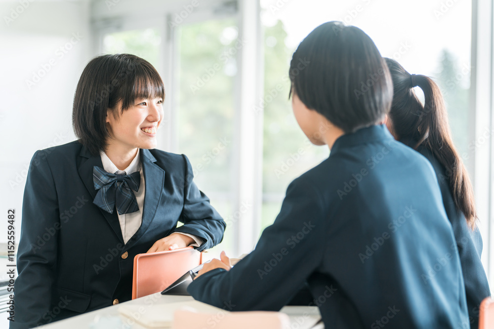 Obraz premium 学校で授業中に後ろの席の生徒と話す小学生・中学生・高校生・女子高生（友達） 