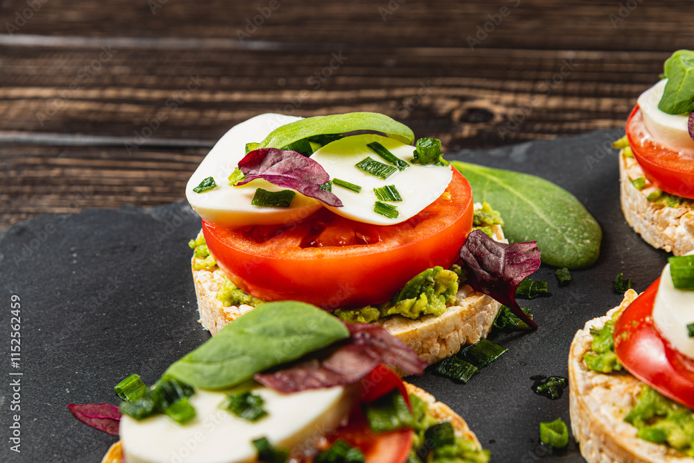 Rice cakes with mozzarella, avocado, spinach, onion on a stone on a wooden table Rice cakes with mozzarella, avocado, spinach, onion on a stone on a wooden table