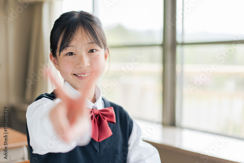 ピースサインをする笑顔の女子中学生 photo