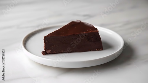 A piece of rich dark chocolate with a smooth texture on a white plate