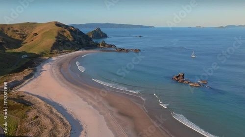 Aerial view of a secluded beach, gentle waves, and a sailboat. Tranquil coastal scene. OPITO BAY, COROMANDEL PENINSULA, NEW ZEALAND photo