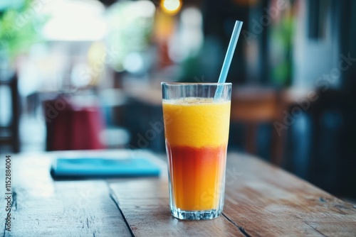 Two-layered orange and red juice in a glass on a wooden table. photo