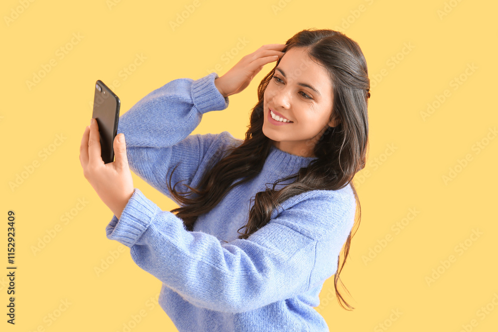 Pretty young woman with mobile phone taking selfie on yellow background Pretty young woman with mobile phone taking selfie on yellow background
