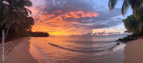 Panoramic view of a vibrant sunset over the beach with palm trees and calm waves creating a serene atmosphere for relaxation and beauty.