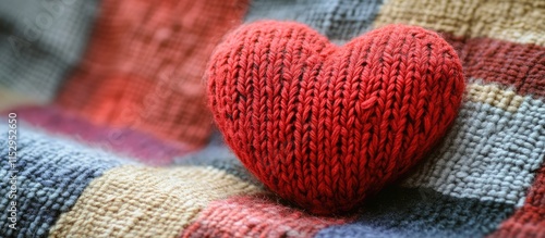 Knitted red heart displayed on a textured checkered pattern creating a warm and cozy ambiance for creative projects or Valentine's Day themes photo