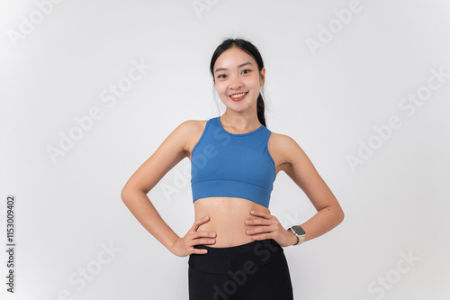 Wallpaper Mural A confident, sporty Asian woman in sportswear smiling at the camera, standing on a studio background Torontodigital.ca