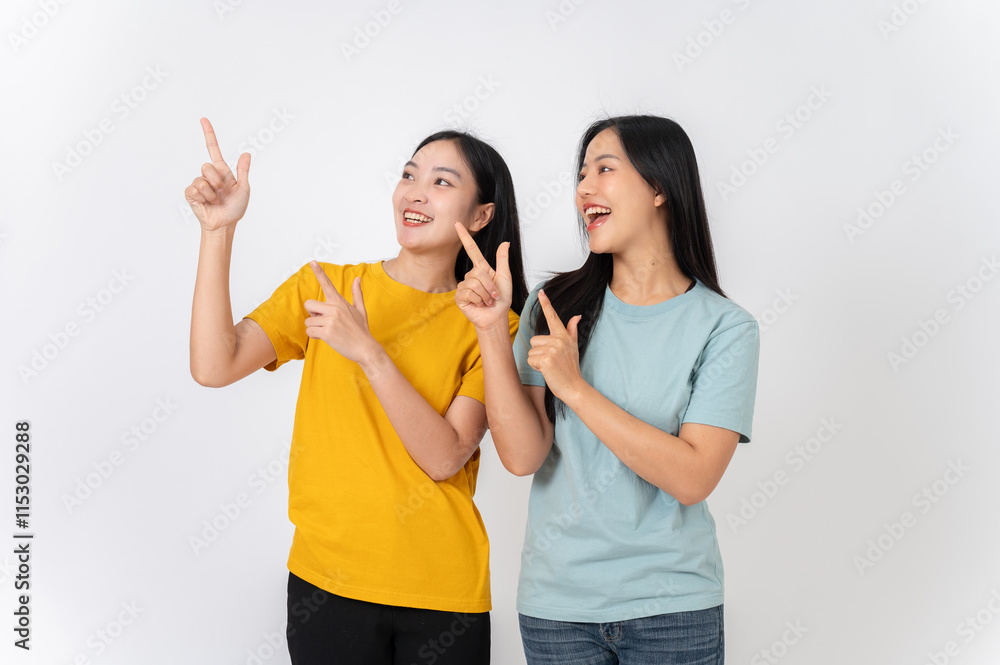 Two cheerful females pointing their finger upward at an empty space, recommending a special offer. Two cheerful females pointing their finger upward at an empty space, recommending a special offer.