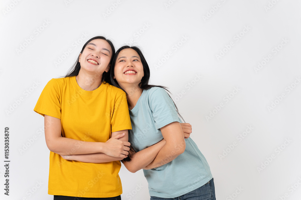 Two lovely, smiling young Asian women standing against on a white studio background. Two lovely, smiling young Asian women standing against on a white studio background.
