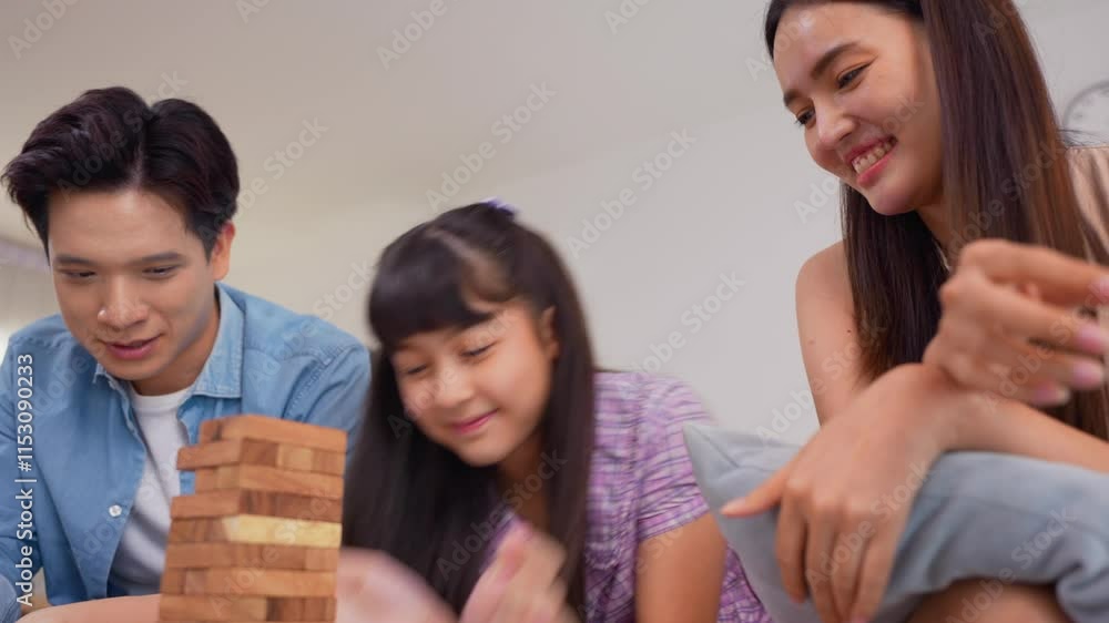Asian loving parents playing wood block game with young daughter in house. Asian loving parents playing wood block game with young daughter in house.