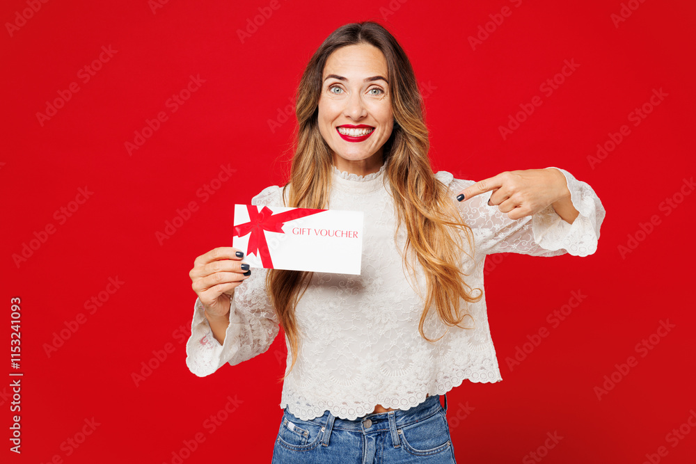 Young smiling happy woman she wear white blouse casual clothes hold point finger on gift certificate coupon voucher card for store isolated on plain red background studio portrait. Lifestyle concept. Young smiling happy woman she wear white blouse casual clothes hold point finger on gift certificate coupon voucher card for store isolated on plain red background studio portrait. Lifestyle concept.