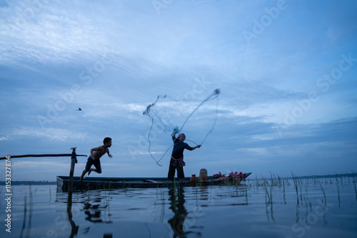 Fisherman casting his net at sunrise. Silhouette Asian fisherman on wooden boat casting a net in the Lake. Vietnamese Fisherman throwing net. photo