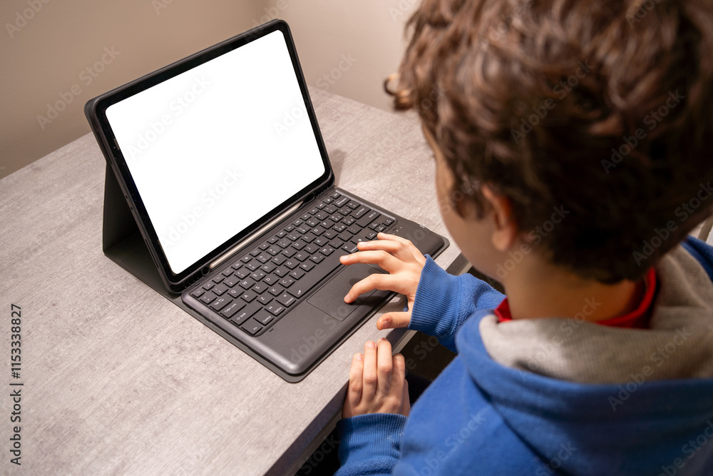 Young boy using internet with a tablet with keyboard for e-learning or web browsing - child looking at device screen online Young boy using internet with a tablet with keyboard for e-learning or web browsing - child looking at device screen online