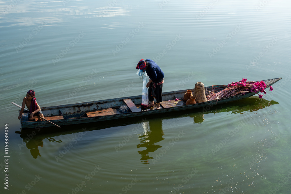 Fisherman casting his net at sunrise. Silhouette Asian fisherman on wooden boat casting a net in the Lake. Vietnamese Fisherman throwing net.