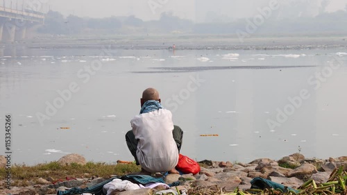 Isolated Man Sitting by Polluted River with Toxic Foam at Morning video is taken at yamuna river okhla barrage delhi india. photo