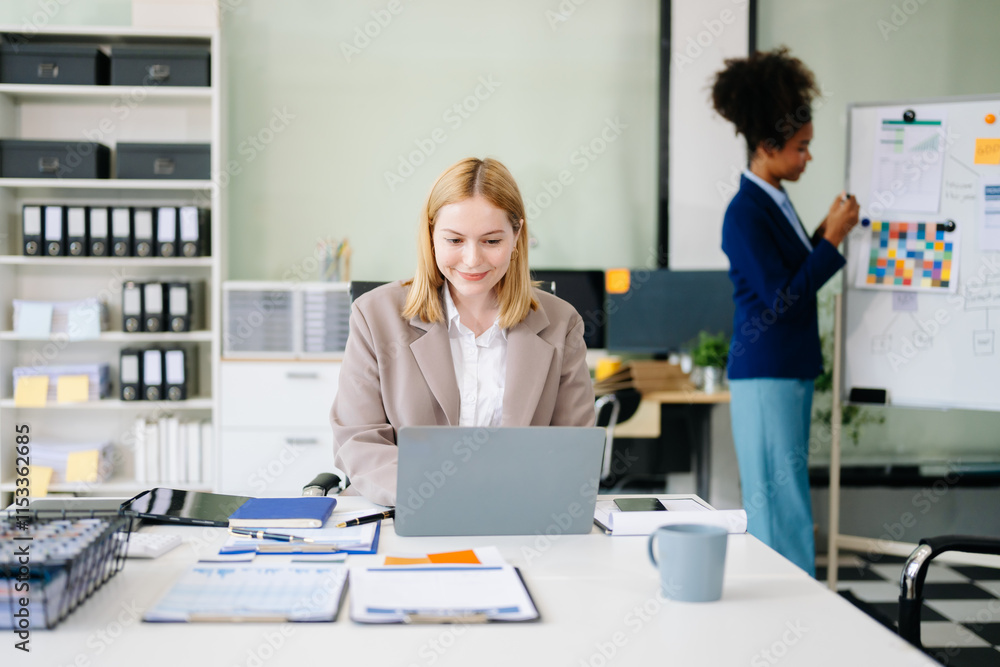 Confident business expert attractive smiling young woman typing laptop and holding digital tablet on desk Confident business expert attractive smiling young woman typing laptop and holding digital tablet on desk