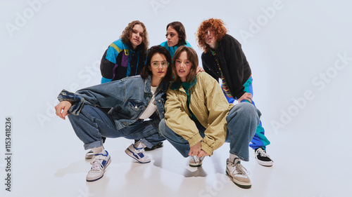 Stylish young people, men and women in oversized jackets, windbreakers and retro sneakers, posing against white studio background. Concept of 90s fashion, youth. Modern take on nostalgic streetwear photo