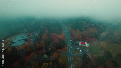 Misty aerial scene of a quiet roadway in Fort Payne, Alabama, winding through colorful autumn foliage beneath low-hanging clouds photo