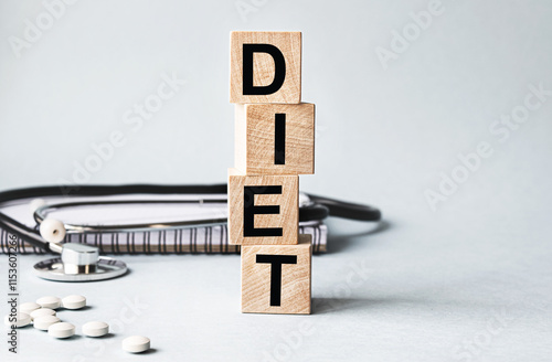 DIET inscription on wooden cubes isolated on white background, medicine concept. Nearby on the table are a stethoscope and pills.