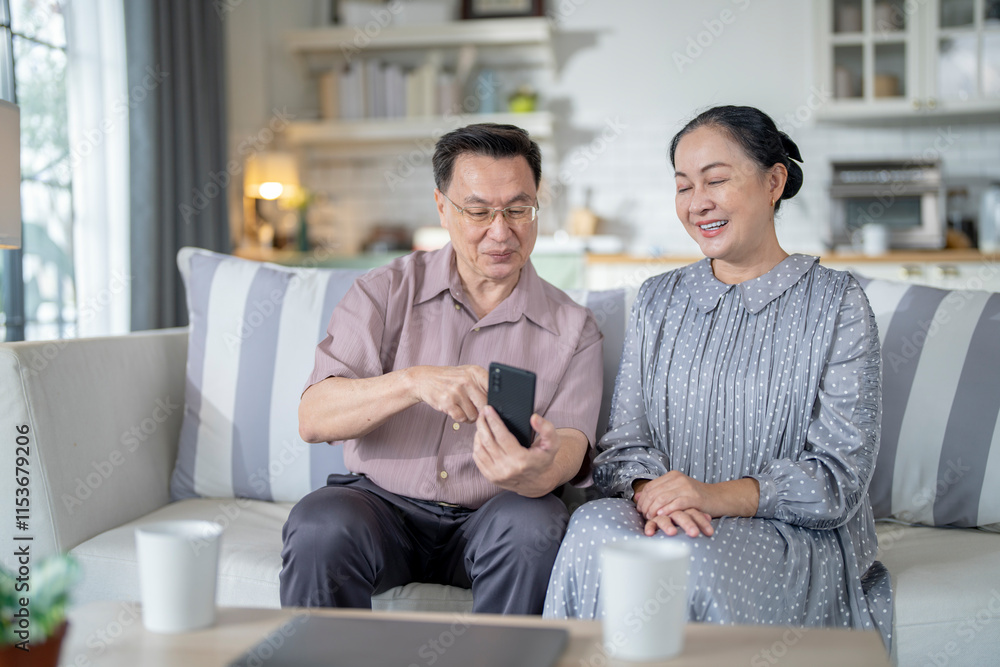 An elderly couple sits together in their cozy living room, smiling and enjoying a moment as they look at something on a smartphone. Their warmth and affection capture a peaceful home atmosphere. An elderly couple sits together in their cozy living room, smiling and enjoying a moment as they look at something on a smartphone. Their warmth and affection capture a peaceful home atmosphere.
