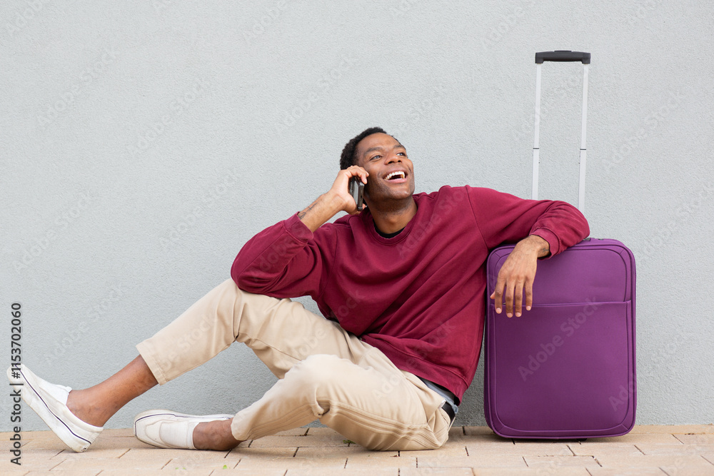 Man sitting with purple suitcase and laughing on the phone Man sitting with purple suitcase and laughing on the phone