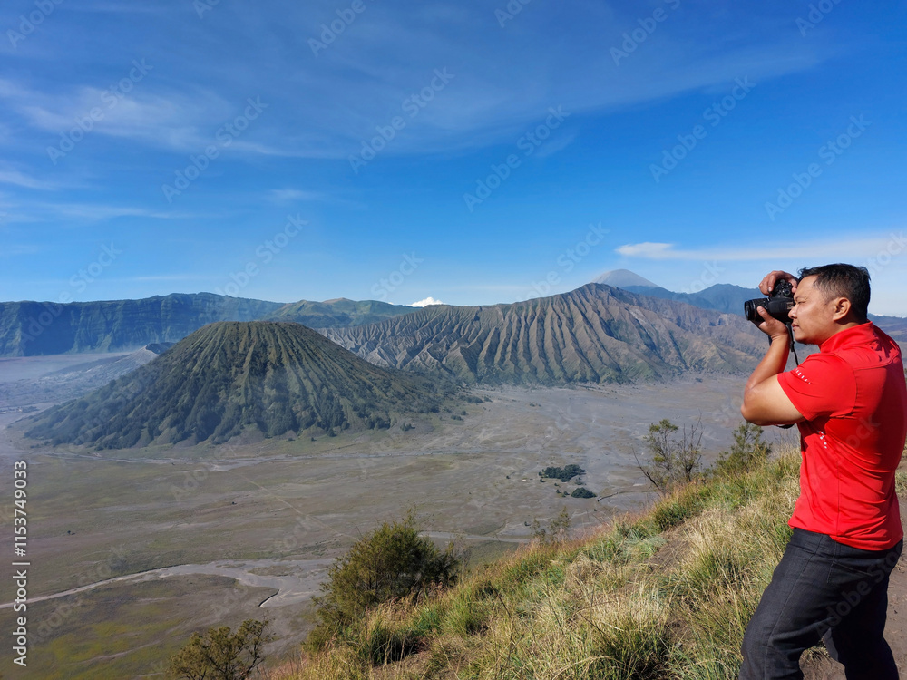Naklejka premium A photographer aims his camera to take a picture of Mount Bromo, one of most popular volcanos in East Java, Indonesia.