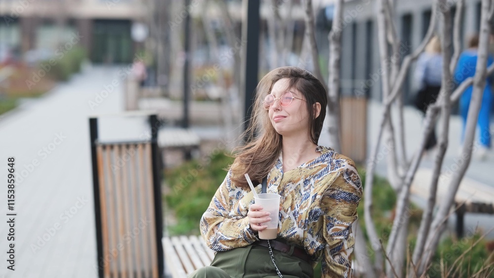 Pensive happy woman sipping a milkshake in the street Pensive happy woman sipping a milkshake in the street