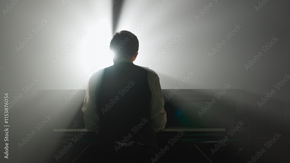 Pianist playing on the black grand piano on dark concert stage against spotlight, back shot isolated on black studio background. Artist performing in concert hall. Pianist playing on the black grand piano on dark concert stage against spotlight, back shot isolated on black studio background. Artist performing in concert hall.