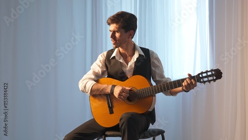 Photography Musician on bright concert stage under spotlight sitting playing on acoustic guitar and singing, isolated on studio background