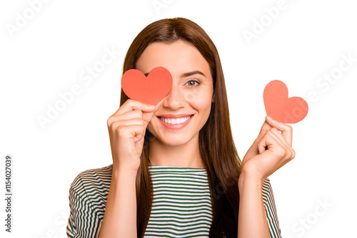 Photo of cute playful girl looking out of one hearts given her as present for valentine day while isolated with yellow background photo