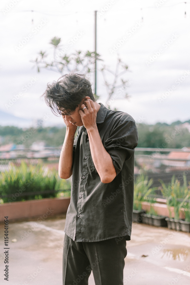 Southeast Asian man cleaning his ear with a cotton swab. Indoor setting, natural light. Southeast Asian man cleaning his ear with a cotton swab. Indoor setting, natural light.